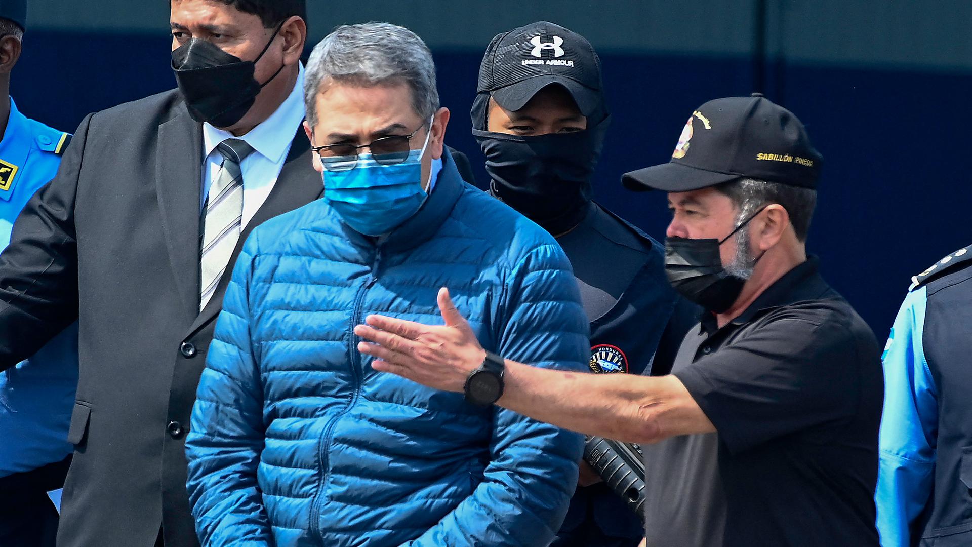 Honduras' früherer Präsident Hernandez wird an die USA ausgeliefert. Auf dem Weg zum Flugzeug weist ihm ein Mann den Weg.