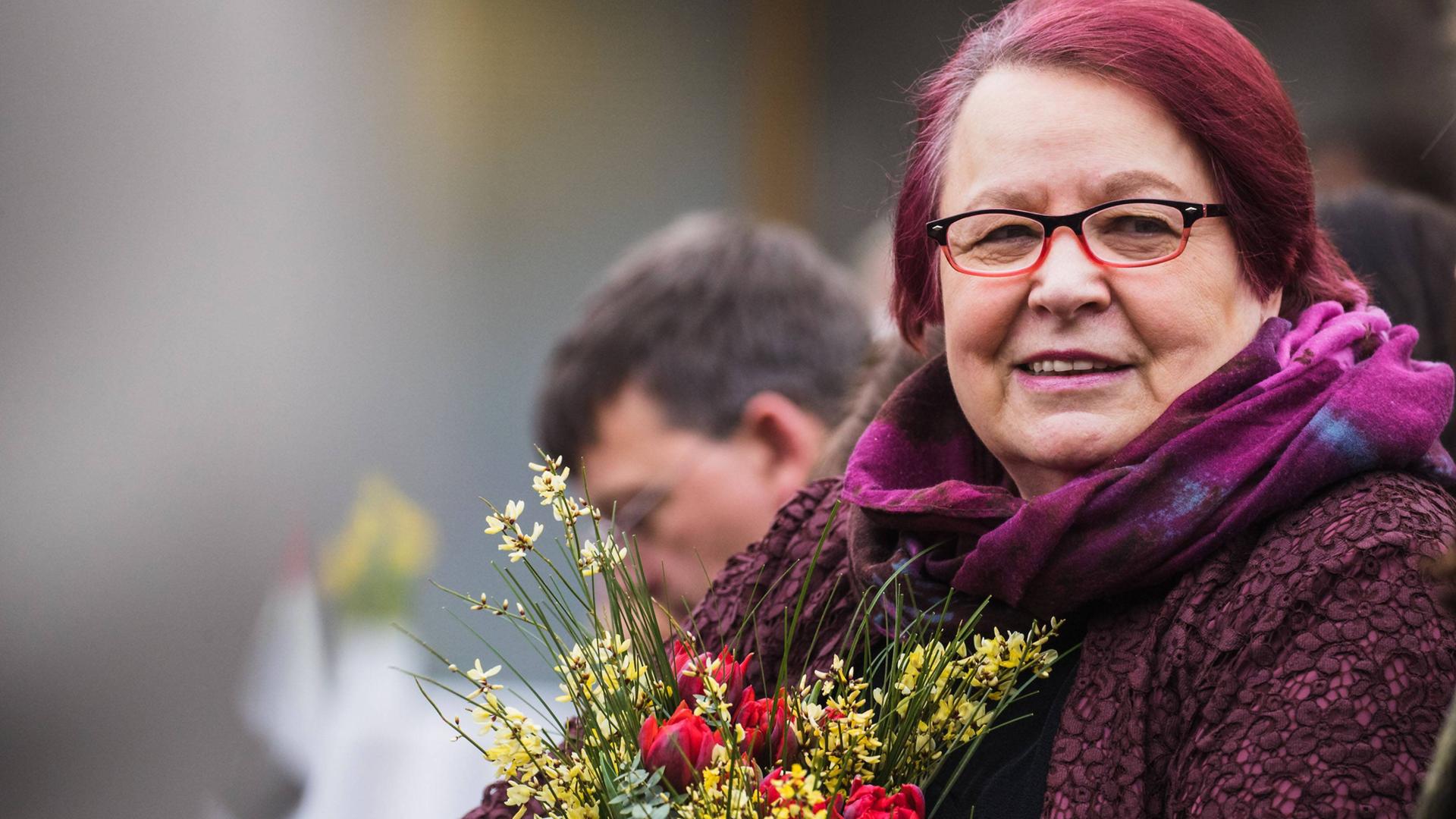 Die Gewinnerin des Preises der Leipziger Buchmesse , Natascha Wodin, hält einen Blumenstrauß in der Hand. Sie trägt eine Brille und lächelt. 