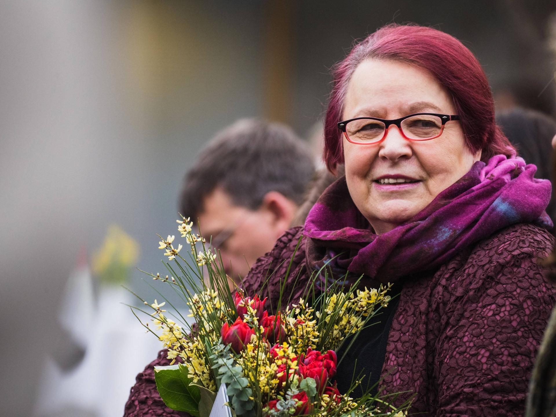 Die Gewinnerin des Preises der Leipziger Buchmesse , Natascha Wodin, hält einen Blumenstrauß in der Hand. Sie trägt eine Brille und lächelt. 