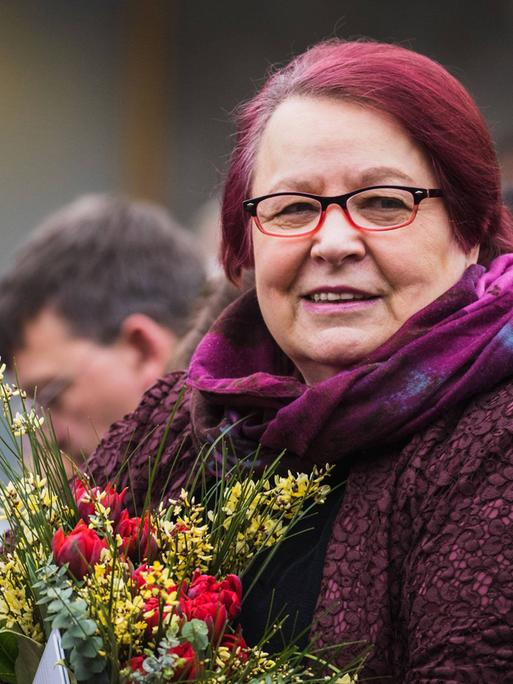 Die Gewinnerin des Preises der Leipziger Buchmesse , Natascha Wodin, hält einen Blumenstrauß in der Hand. Sie trägt eine Brille und lächelt. 