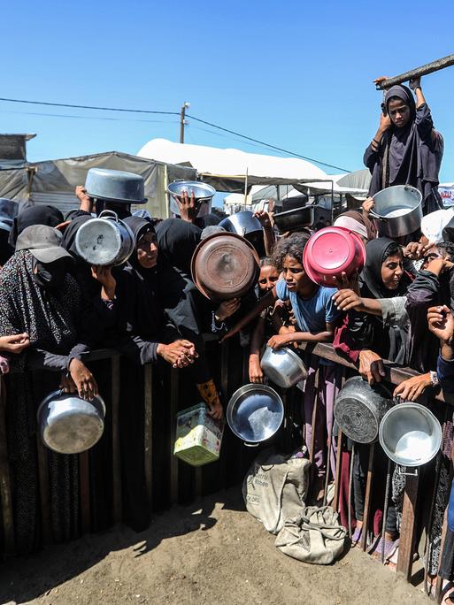 Menschen in Gaza halten leere Schüsseln und Töpfe in der Hand und warten auf die Essensausgabe am 14. September 2025