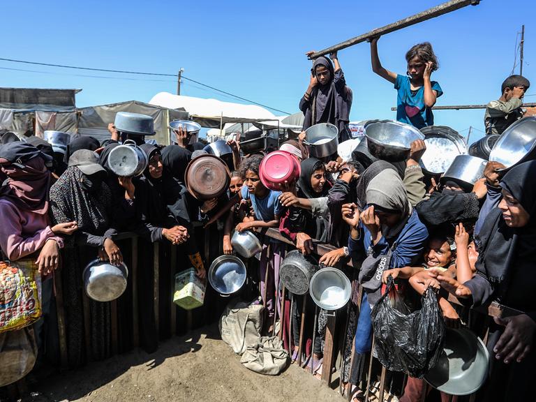 Menschen in Gaza halten leere Schüsseln und Töpfe in der Hand und warten auf die Essensausgabe am 14. September 2025