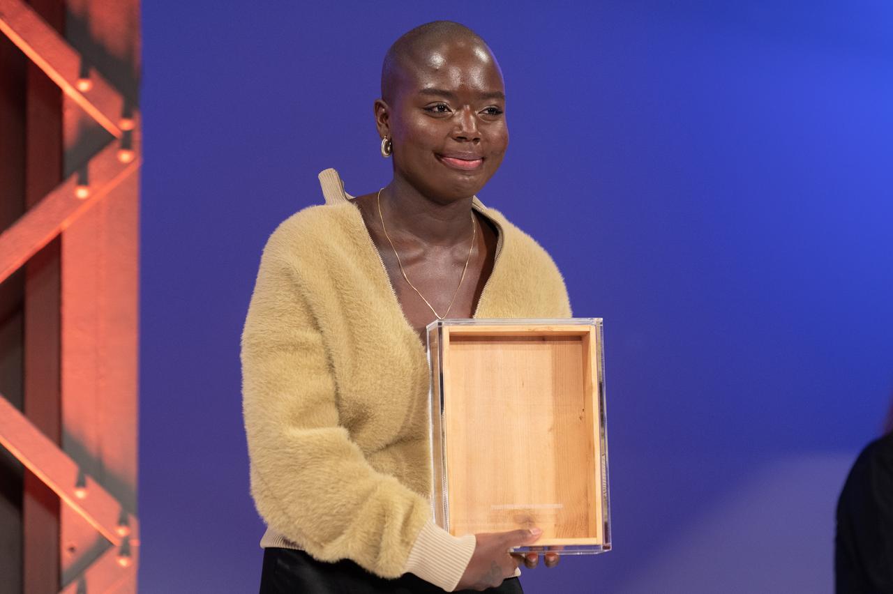 Die Künstlerin Sandra Mujinga hält einen schubladenartigen Gegenstand in der Hand. Es ist der Preis der Nationalgalerie 2021.