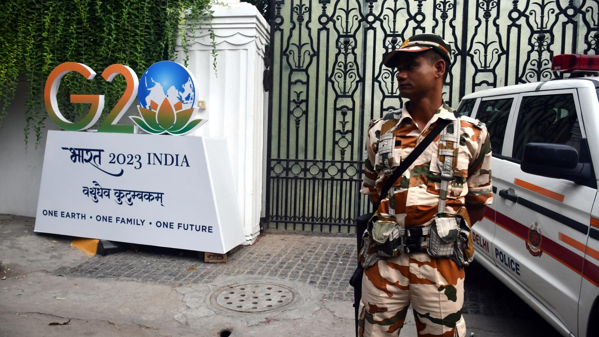 Ein Soldat steht neben dem Logo des G20-Gipfels in Indien.