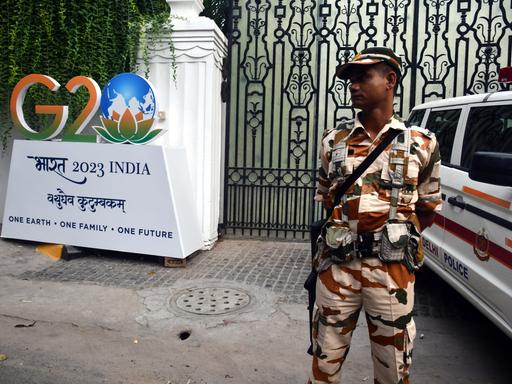 Ein Soldat steht neben dem Logo des G20-Gipfels in Indien.