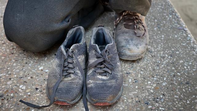 Ein Mann kniet hinter einem Paar Kinderschuhe. Ein Mann kniet hinter einem Paar Kinderschuhe.