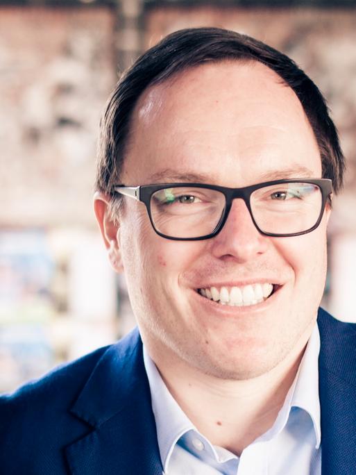 Zu sehen ist der Journalist Daniel Drepper. er trägt eine Brille und lächelt.