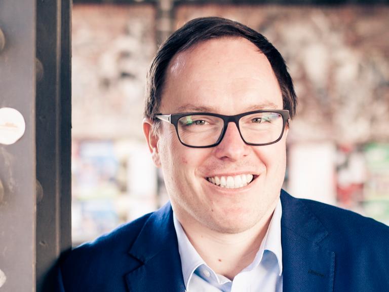 Zu sehen ist der Journalist Daniel Drepper. er trägt eine Brille und lächelt.