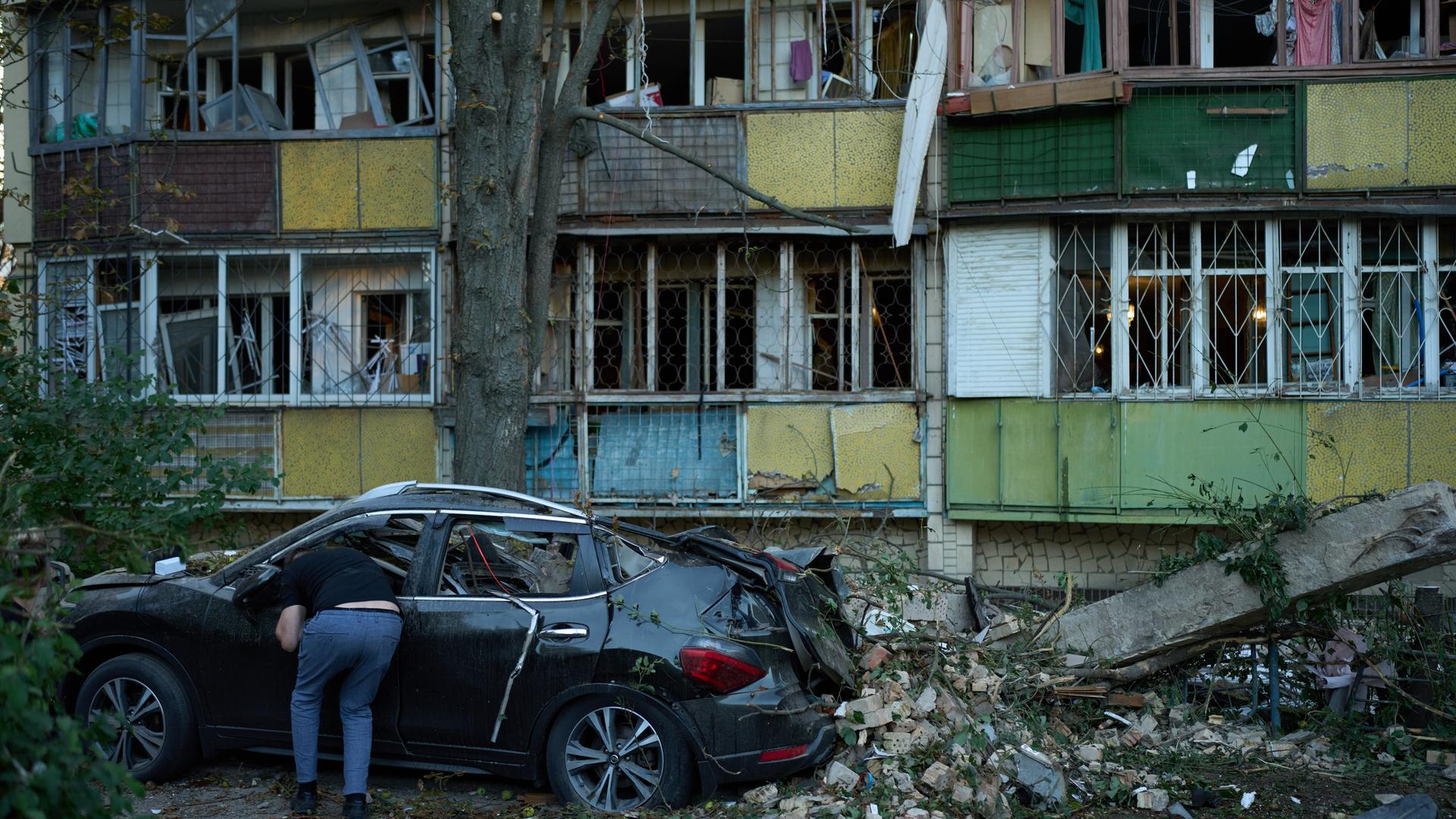 Ukraine, Kiew: Ein Anwohner blickt nach einem nächtlichen russischen Angriff in ein zerstörtes Auto neben schwer beschädigten Wohngebäuden. Ukraine, Kiew: Ein Anwohner blickt nach einem nächtlichen russischen Angriff in ein zerstörtes Auto neben schwer beschädigten Wohngebäuden.