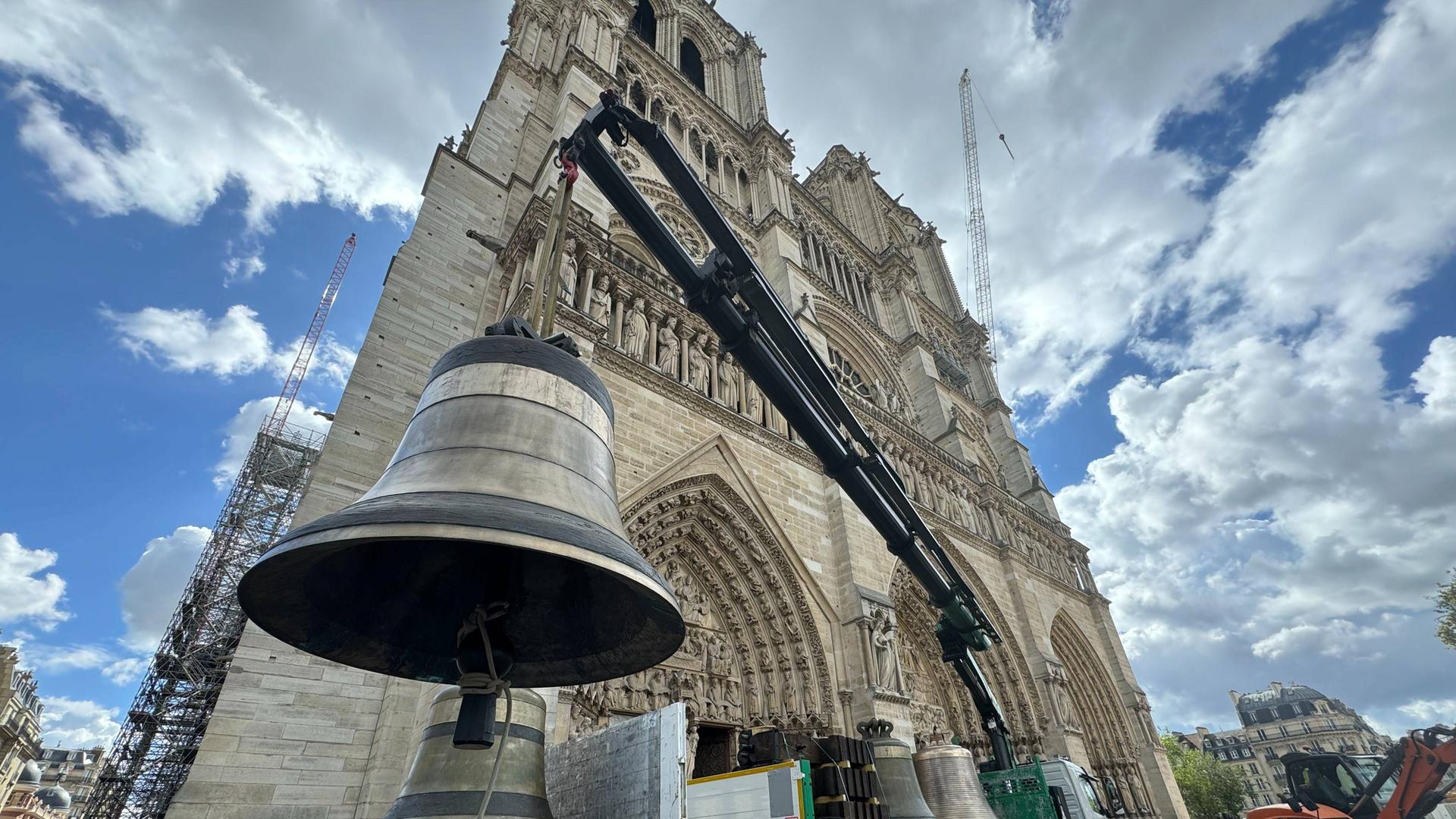 Eine Glocke hängt vor der Pariser Kathedrale Notre-Dame am Seil von einem Kran. 