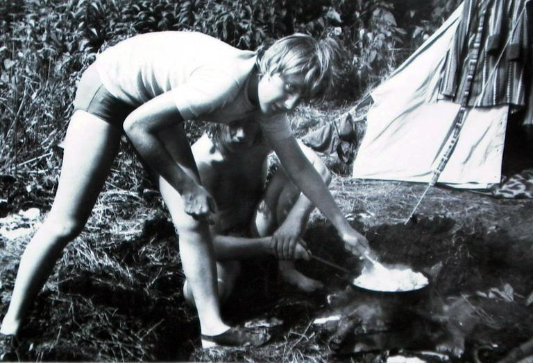 Eine junge Frau rührt in einer Pfanne auf einem Campingkocher