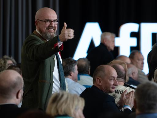 Hans-Thomas Tillschneider ist Landtagsabgeordneter der AfD Sachsen-Anhalt. Der bärtige Mann mit Glatze in tannengrünem Jacket macht das Daumen-hoch-Zeichen und grinst auf dem Landesparteitag in Weißandt-Gölzau am 22. April 2023.