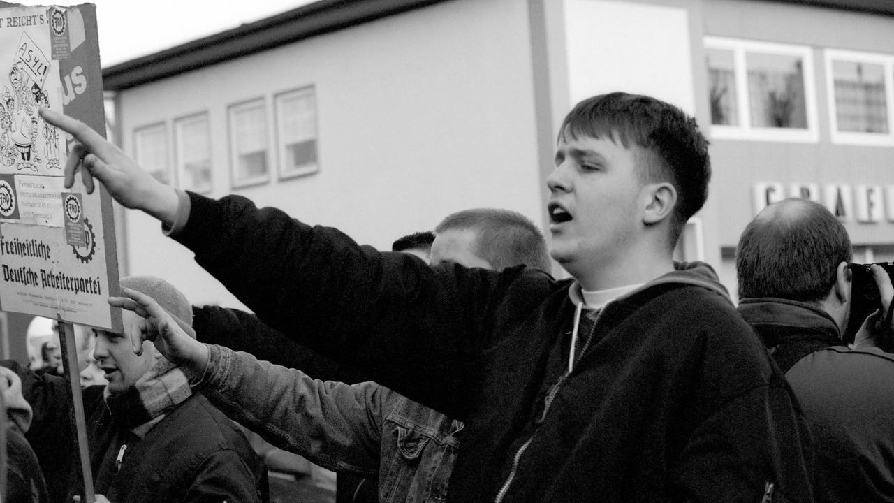 Ein junger Rechtsextremer hebt den Arm in einer Geste die dem Hitlergruß ähnelt.