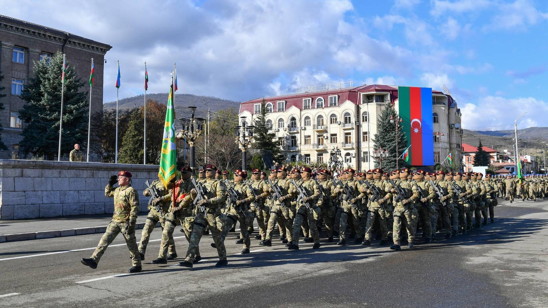 Aserbaidschanische Soldaten marschieren über eine Straße.