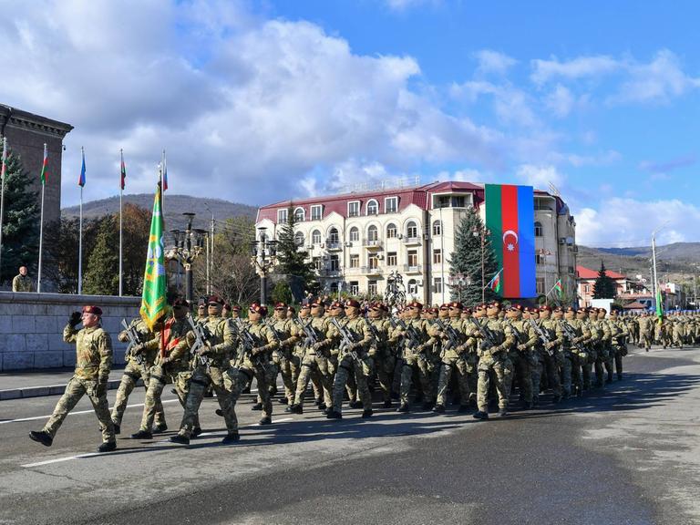 Aserbaidschanische Soldaten marschieren über eine Straße.