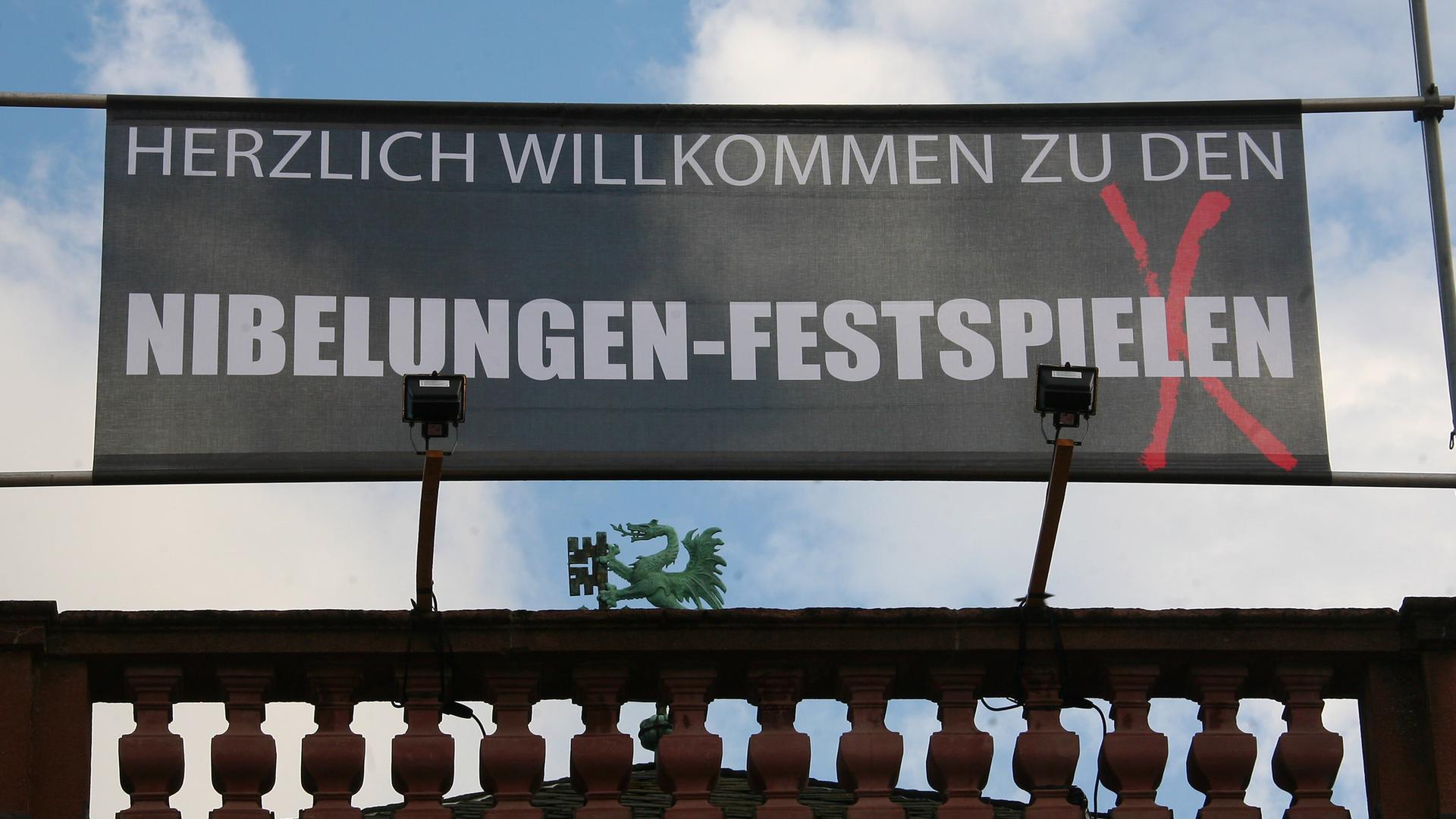 Auf einem Banner über einem Dach steht "Willkommen zu den Niebelungen-Festspielen" Auf einem Banner über einem Dach steht "Willkommen zu den Niebelungen-Festspielen"