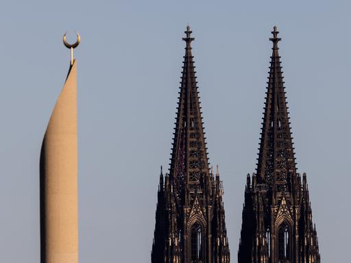 Im Licht in der untergehenden Sonne sind ein Minarett der Zentralmoschee die beiden Türme des Kölner Doms zu sehen. 