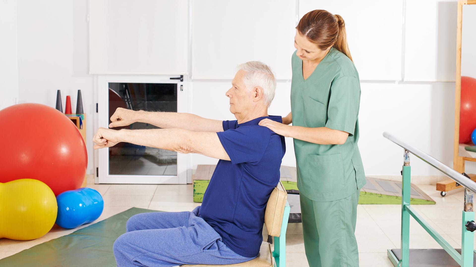 Senior beim Rehasport macht Rückenübung mit Physiotherapeutin im Pflegeheim Senior beim Rehasport macht Rückenübung mit Physiotherapeutin im Pflegeheim