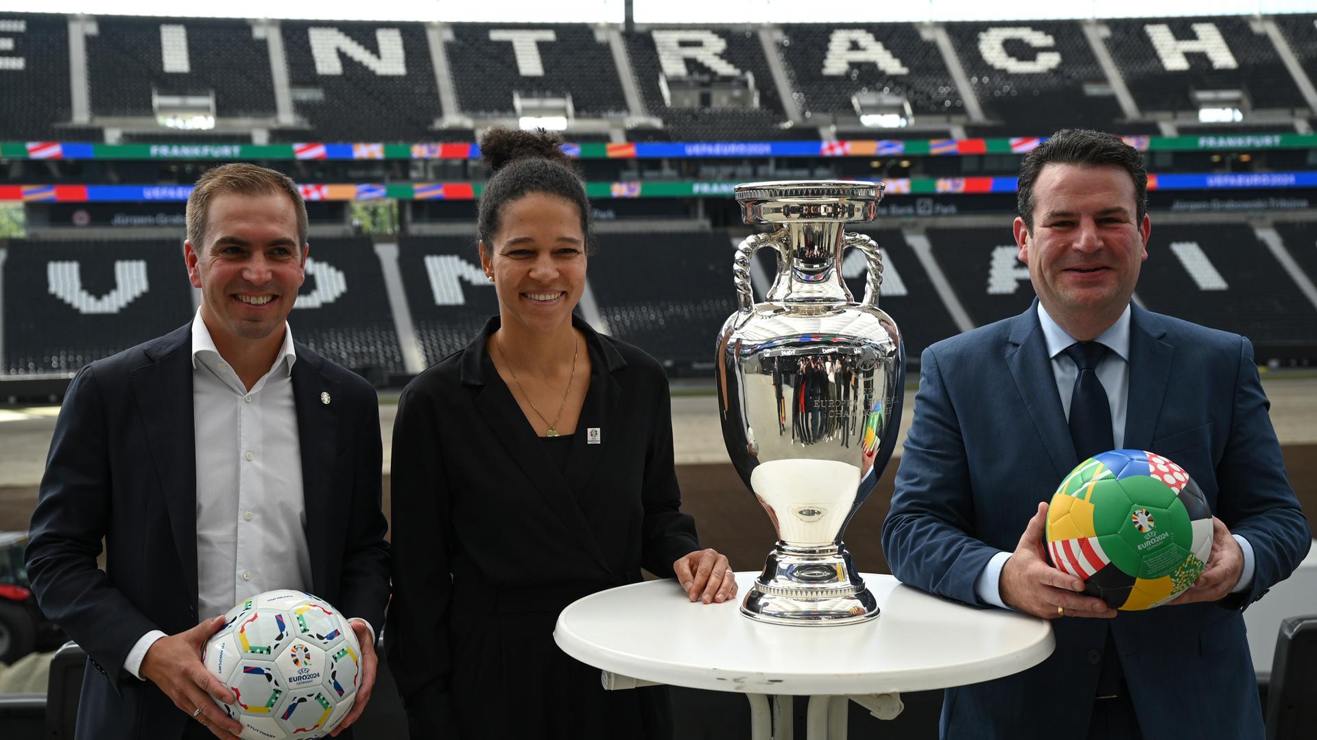 Lahm, Šašić und Heil stehen im Anschluss an eine Pressekonferenz zur EM 2024 mit dem Pokal und Fußbällen im Frankfurter Stadion.