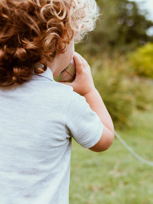 Ein Junge spricht in ein Dosentelefon.