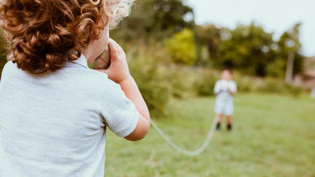 Ein Junge spricht in ein Dosentelefon.