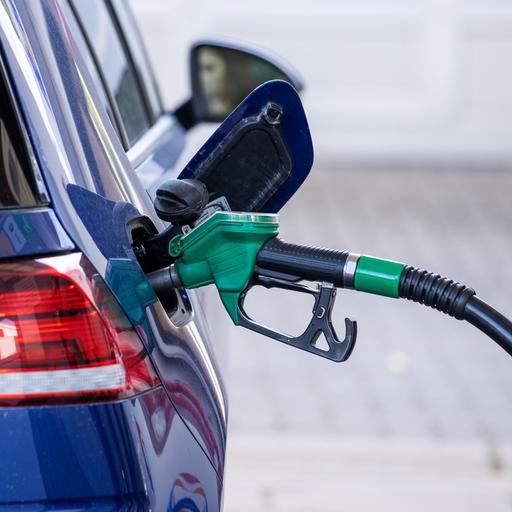 Eine Zapfpistole für Benzin steckt in einer Tankstelle im Tankstutzen eines Autos. 