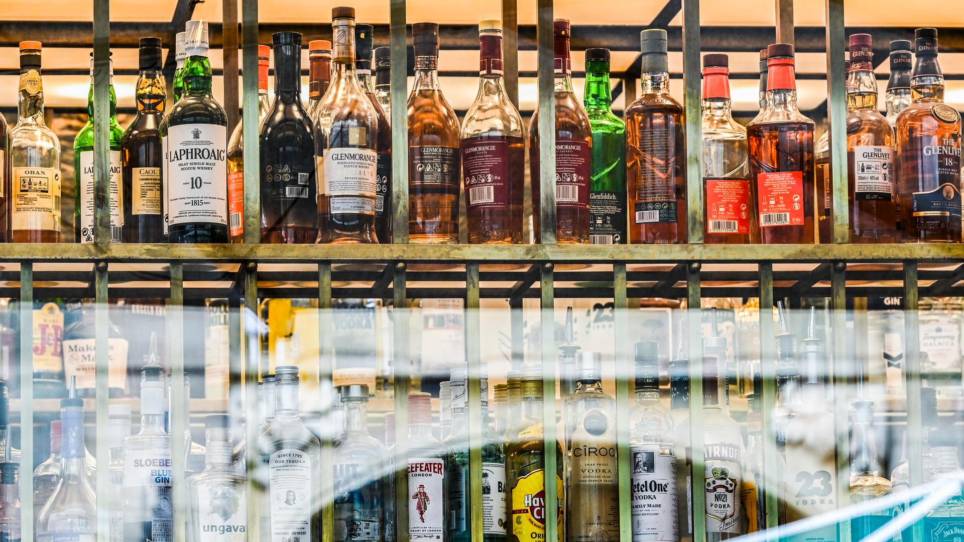 Flaschen mit verschieden Sorten Alkohol sind hinter Fensterscheiben einer Bar zu sehen. Flaschen mit verschieden Sorten Alkohol sind hinter Fensterscheiben einer Bar zu sehen.