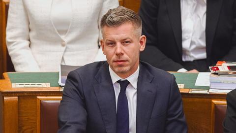 Peter Magyar sitzt im ungarischen Parlament. Er trägt einen Anzug und lächelt. Hinter ihm sitzen andere Menschen.