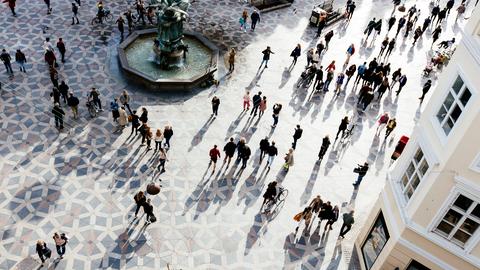 Blick von oben auf den Hauptplatz von Amagertorv im Abendlicht. Die langen Schatten der Fußgänger*innen bilden sich auf dem gemusterten Boden ab.