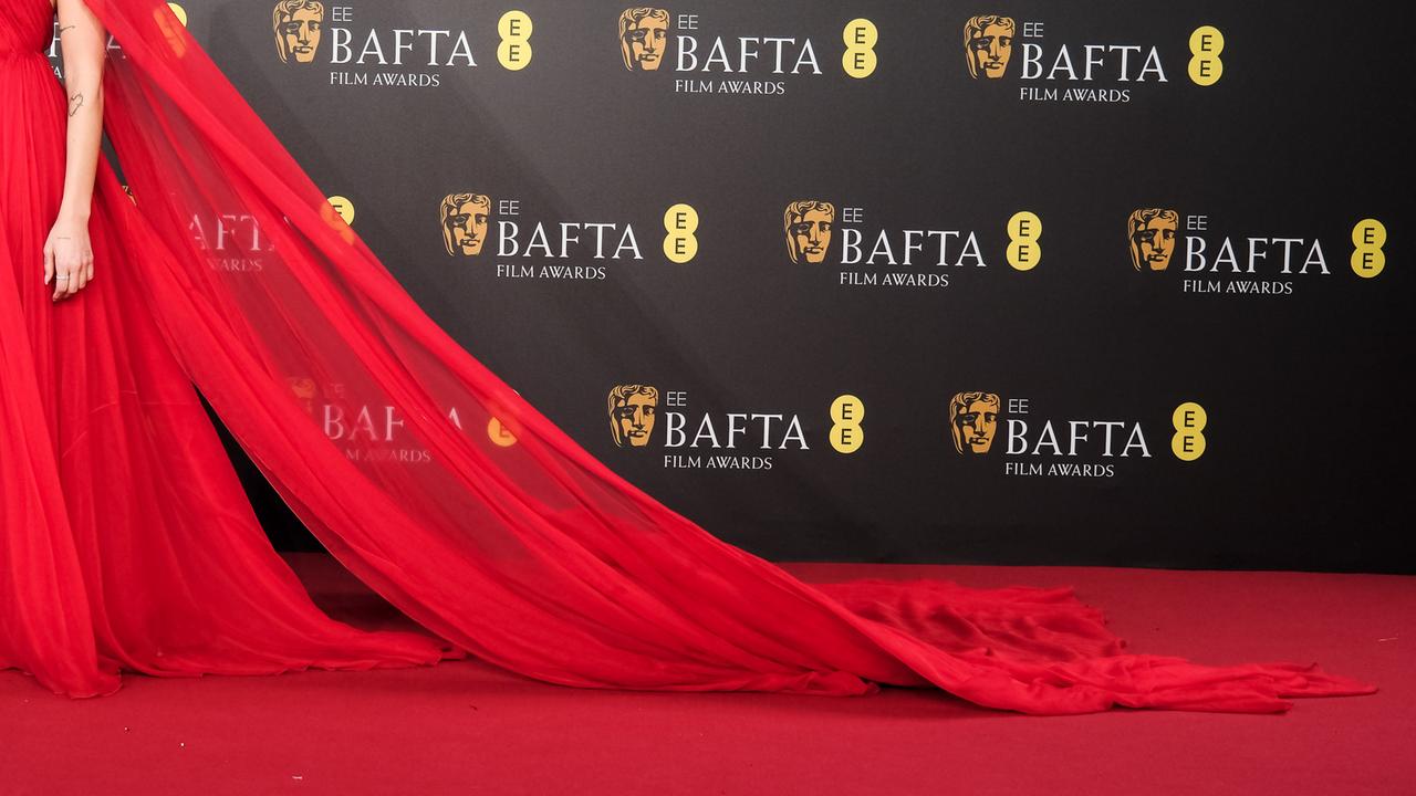 Man sieht eine Frau in einem roten Abendkleid bei den BAFTA Film Awards.