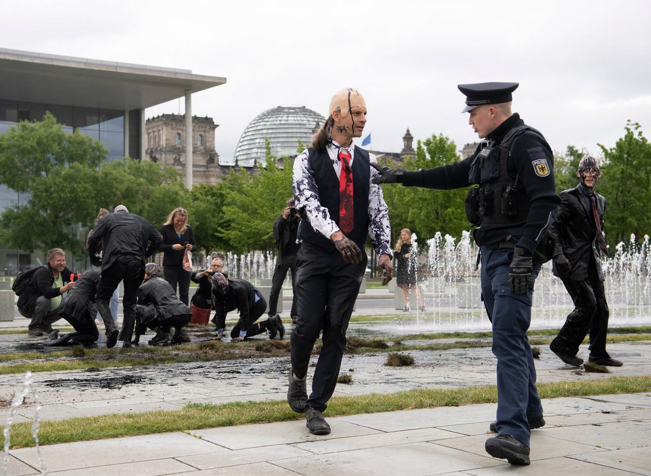 Polizeibeamte stehen vor dem Kanzleramt bei Klimaschutz-Aktivisten der Gruppe "Letzte Generation". Zuvor hatten die Aktivisten als Bundeskanzler Scholz verkleidet vor dem Kanzleramt eine öl-ähnliche Farbsubstanz verschüttet, die Grasflächen aufgerissen, um nach eigenen Angaben nach Öl zu bohren.