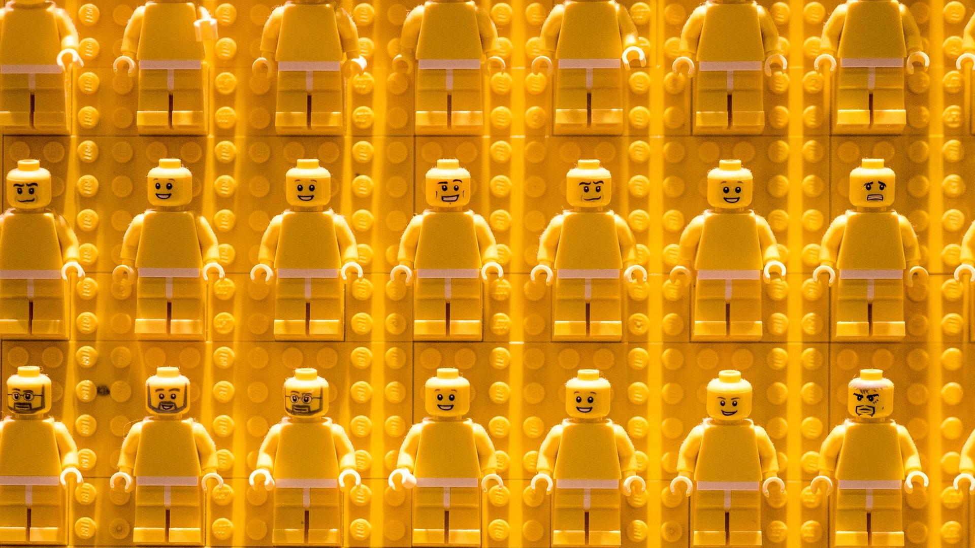 Reihen von gelben Legofiguren vor gelbem Legohintergrund.