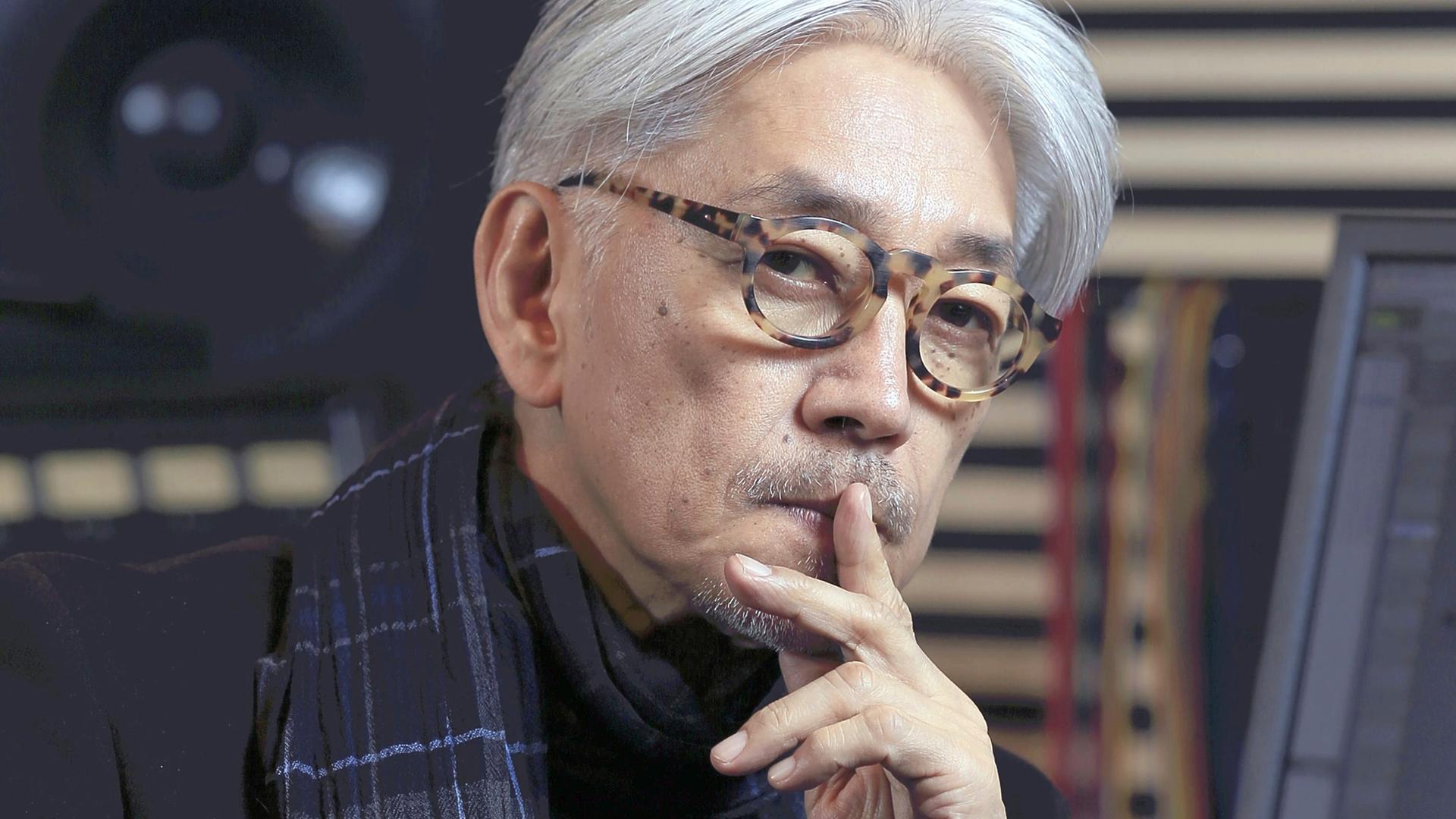 Portraitaufnahme eines älteren weißhaarigen japanischen Mannes, er legt den Finger auf die Lippen