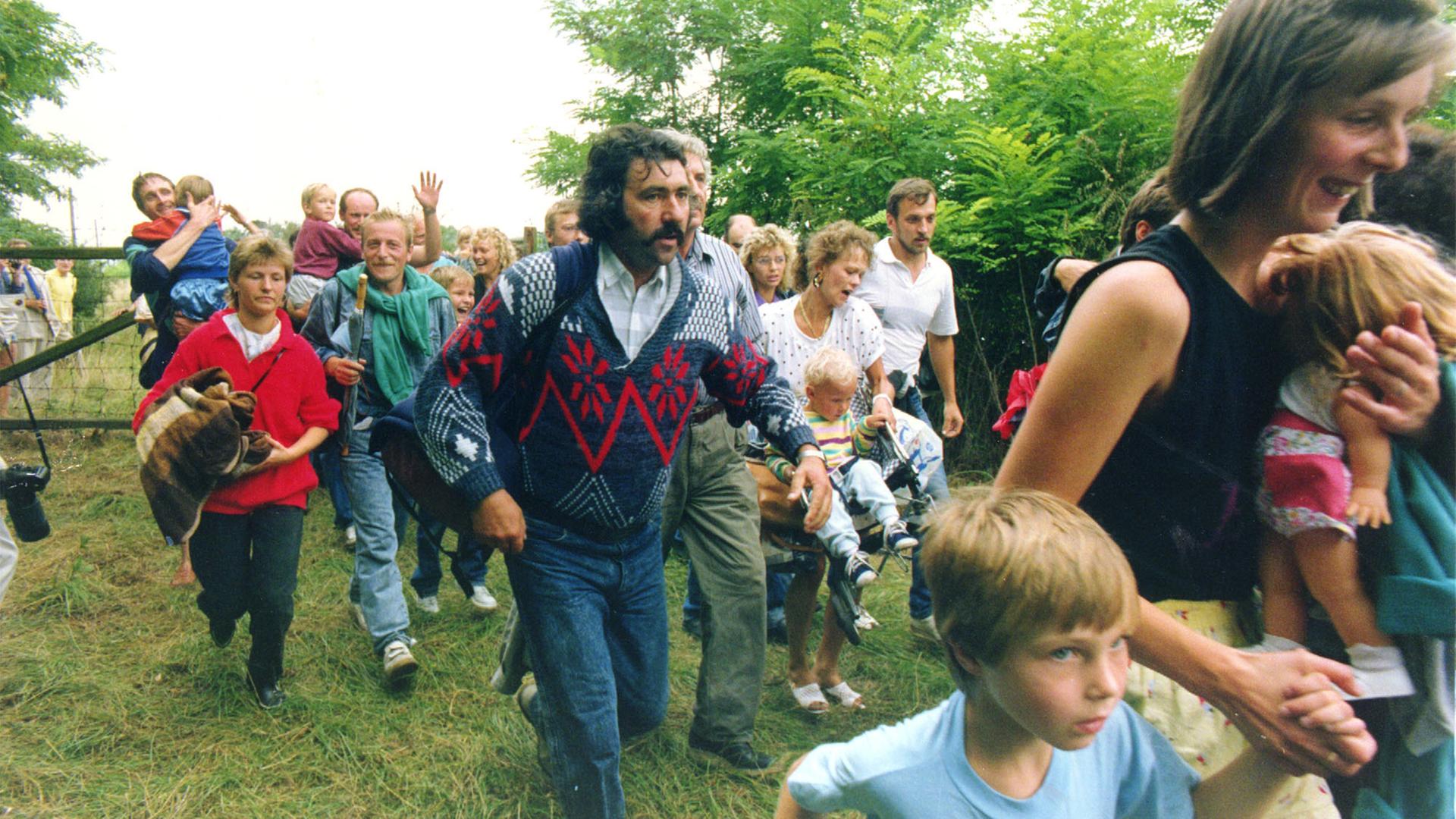 Mehrere Hundert DDR-Bürger rennen am 19. August 1989 im Laufschritt durch ein Holztor über die ungarisch-österreichische Grenze nach Mörbisch auf der oesterreichischen Seite.