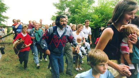 Mehrere Hundert DDR-Bürger rennen am 19. August 1989 im Laufschritt durch ein Holztor über die ungarisch-österreichische Grenze nach Mörbisch auf der oesterreichischen Seite.