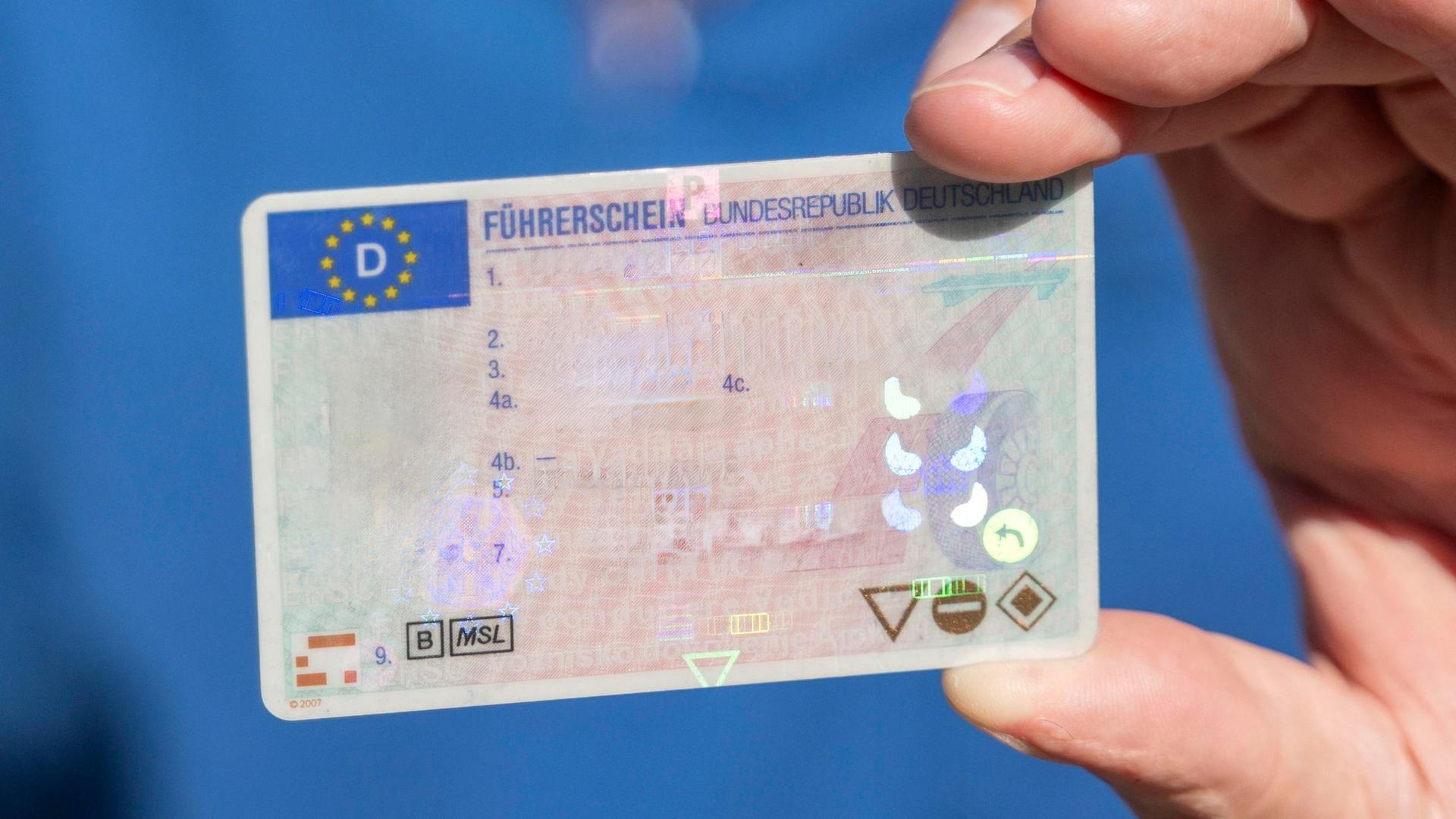 Ein Mann hält einen Führerschein der Bundesrepublik Deutschland in der Hand.