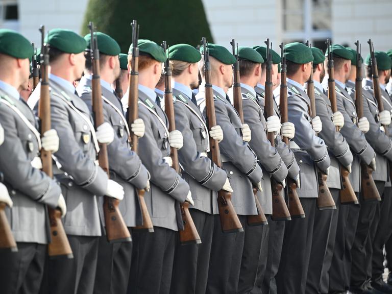 Soldatinnen und Soldaten der Bundeswehr stehen mit Gewehren auf einem offiziellen Empfang.