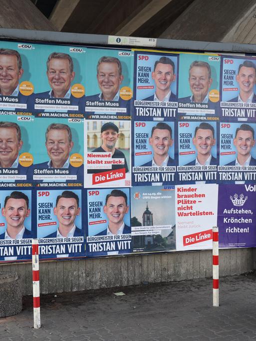 Wahlplakate zeigen die Köpfe mehrerer Kandidaten für das Bürgermeisteramt der Stadt Siegen in Nordrhein-Westfalen