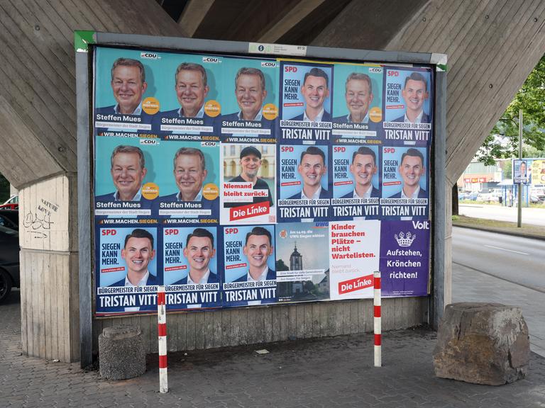 Wahlplakate zeigen die Köpfe mehrerer Kandidaten für das Bürgermeisteramt der Stadt Siegen in Nordrhein-Westfalen