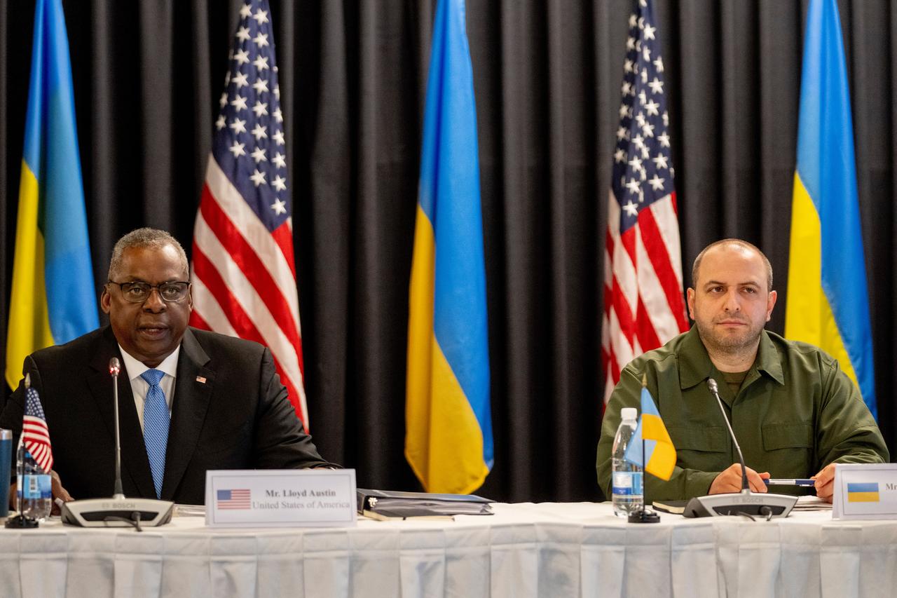 US-Verteidigungsminister Lloyd Austin und sein ukrainischer Kollege Rustem Umerow sitzen nebeneinander, hinter ihnen die Nationalflaggen ihrer beiden Länder.