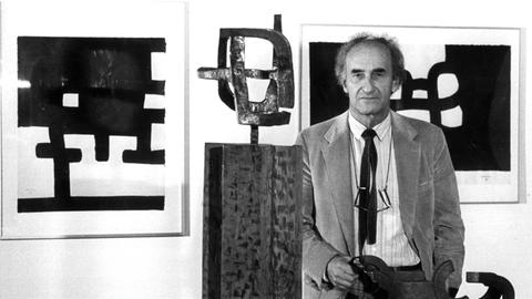 Eduardo Chillida steht zwischen seinen Skulpturen, historische Schwarzweißaufnahme