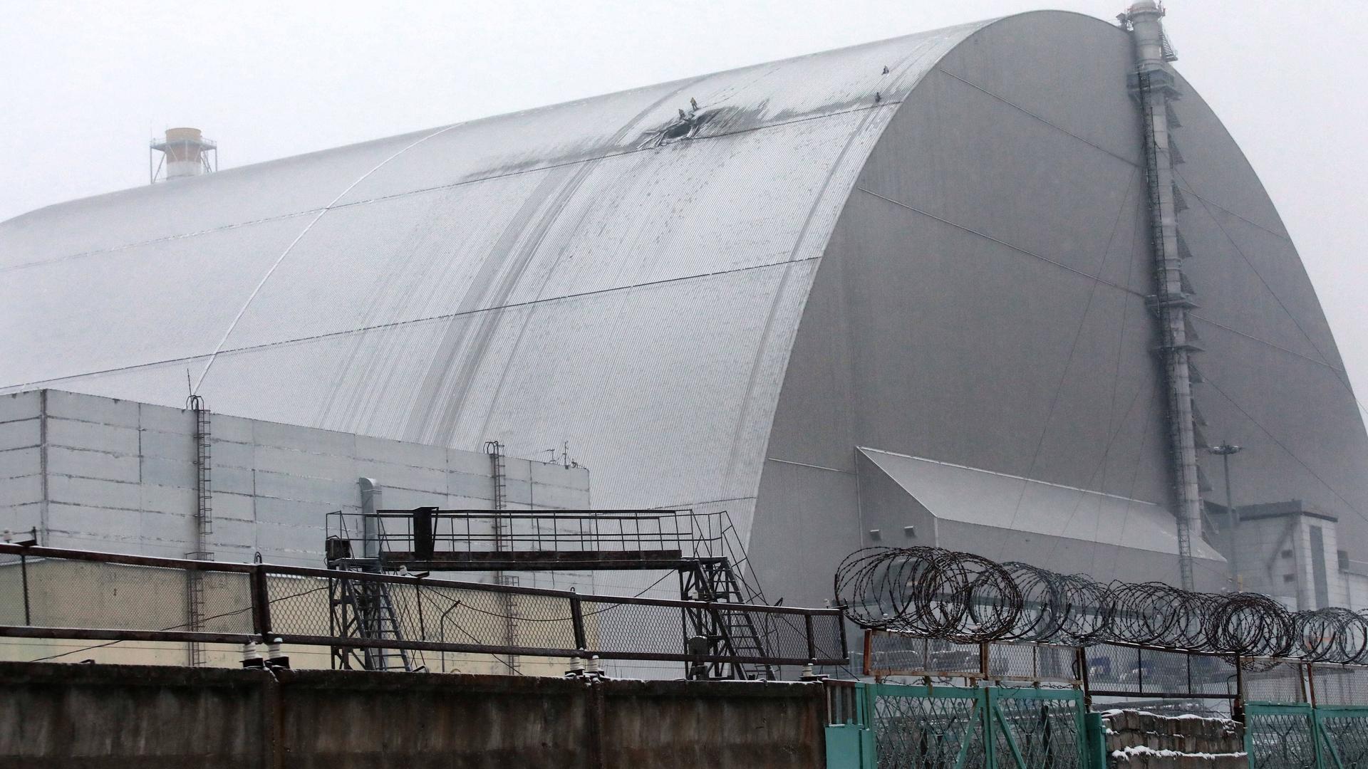 Das Foto zeigt die Schutzhülle um den havarierten Reaktor von Tschernobyl. In der Hülle ist ein Loch erkennbar.