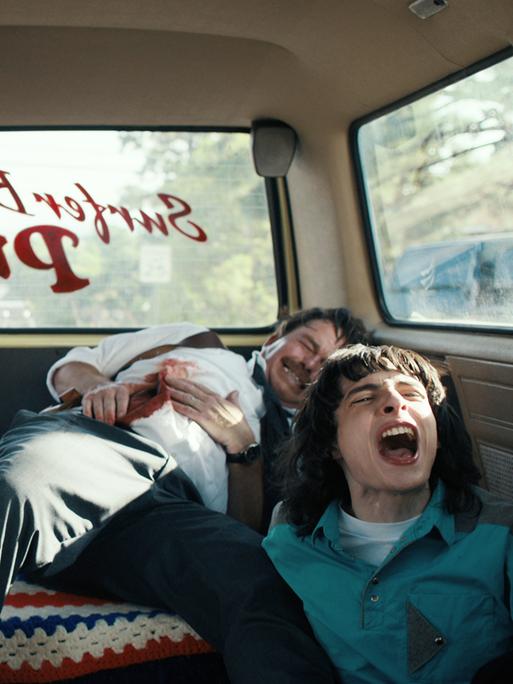 Filmstill: Charlie Heaton als Johnathan Byers, Noah Schnapp als Will Byers and Finn Wolfhard als Mike Wheeler sitzen schreiend im Auto. "Stranger Things" Staffel 4, 2022.