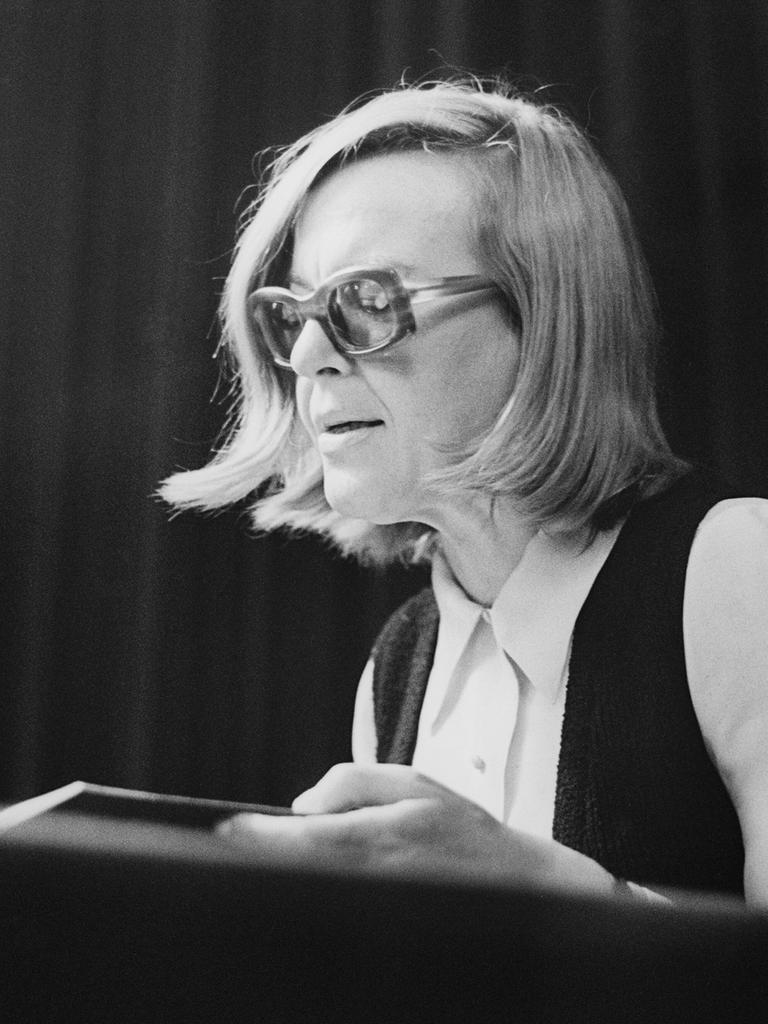 Historisches Schwarzweißfoto von Ingeborg Bachmann bei einer Lesung 1971 in Wien . Sie sitzt sehr aufrecht und trägt eine Brille mit dickem Rahmen.