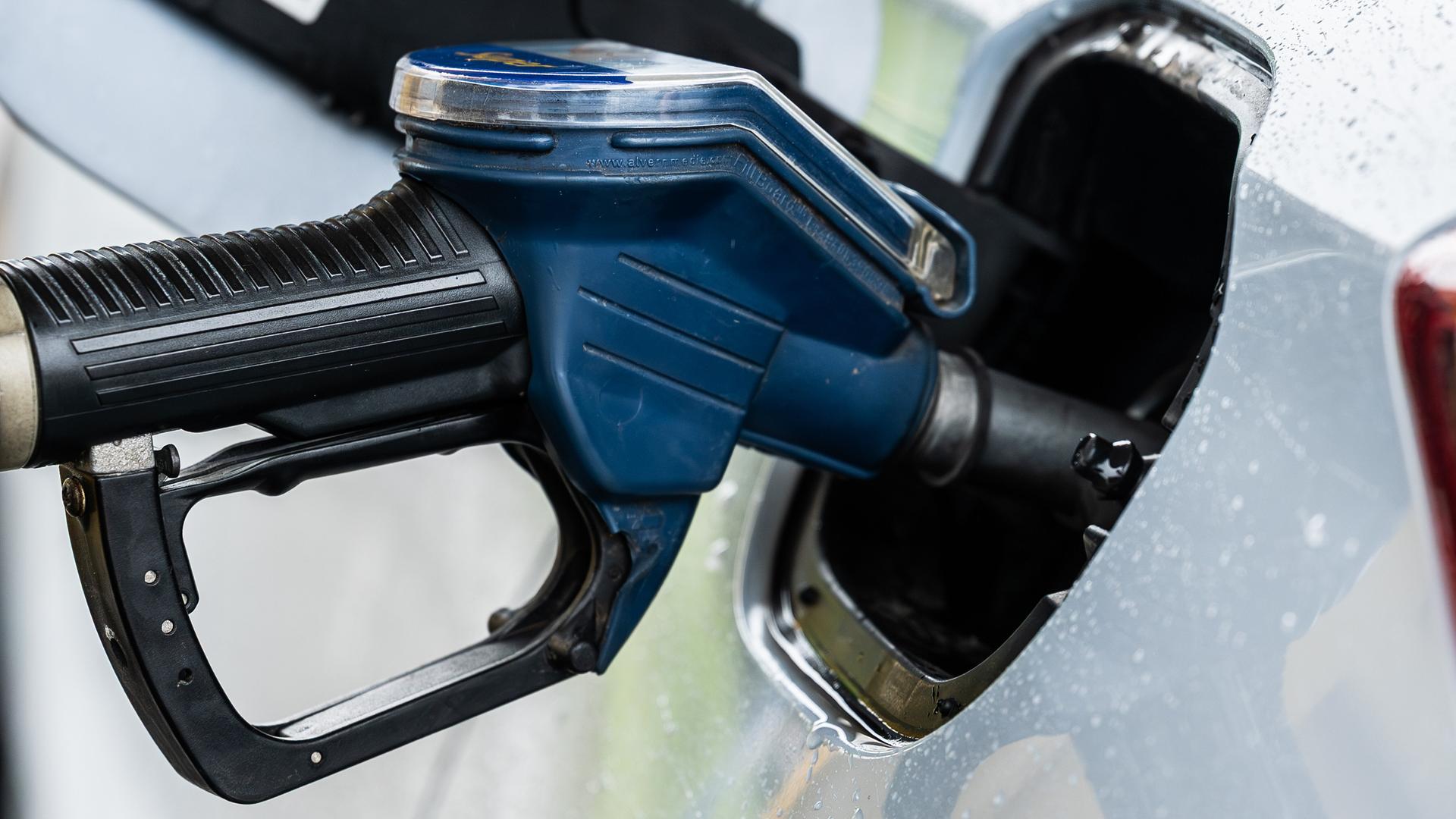 Ein Auto wird an einer Zapfsäule mithilfe eines Tankrüssels an einer Tankstelle betankt.