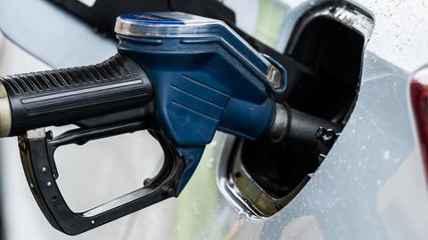 Ein Auto wird an einer Zapfsäule mithilfe eines Tankrüssels an einer Tankstelle betankt.