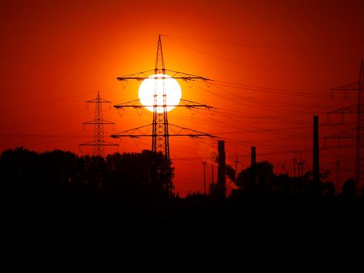 Strommasten in der untergehenden Sonne zu sehen von einem Feld unweit des RWE-Kohlekraftwerk Niederaußem bei Bergheim. 