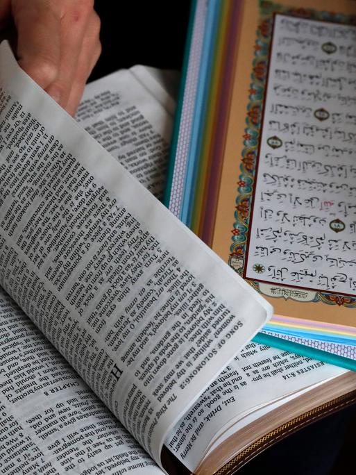 Eine Bibel und ein Koran liegen aufgeschlagen nebeneinander.