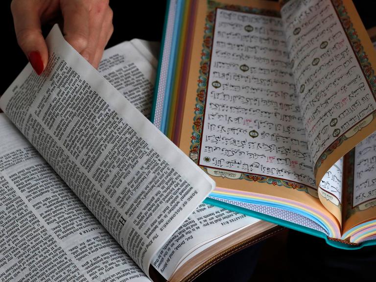 Eine Bibel und ein Koran liegen aufgeschlagen nebeneinander.