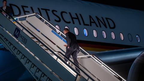 Bundeskanzler Merz steigt in den Regierungsflieger, auf dem in Großbuchstaben "Deutschland" steht. Es ist dunkel. 